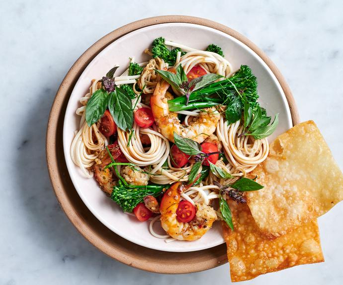 Aerial view of a bowl of noodles with prawns, mint and tomatoes.