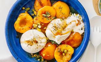 peach burrata salad of roast yellow peaches and burrata cheese in bright blue ceramic bowl